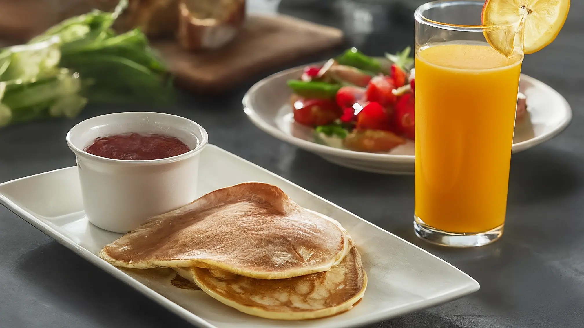 Una pila de panqueques de calabacín dorados, ligeramente espolvoreados con azúcar glas, junto a un vaso de jugo de naranja y un plato con bayas frescas.