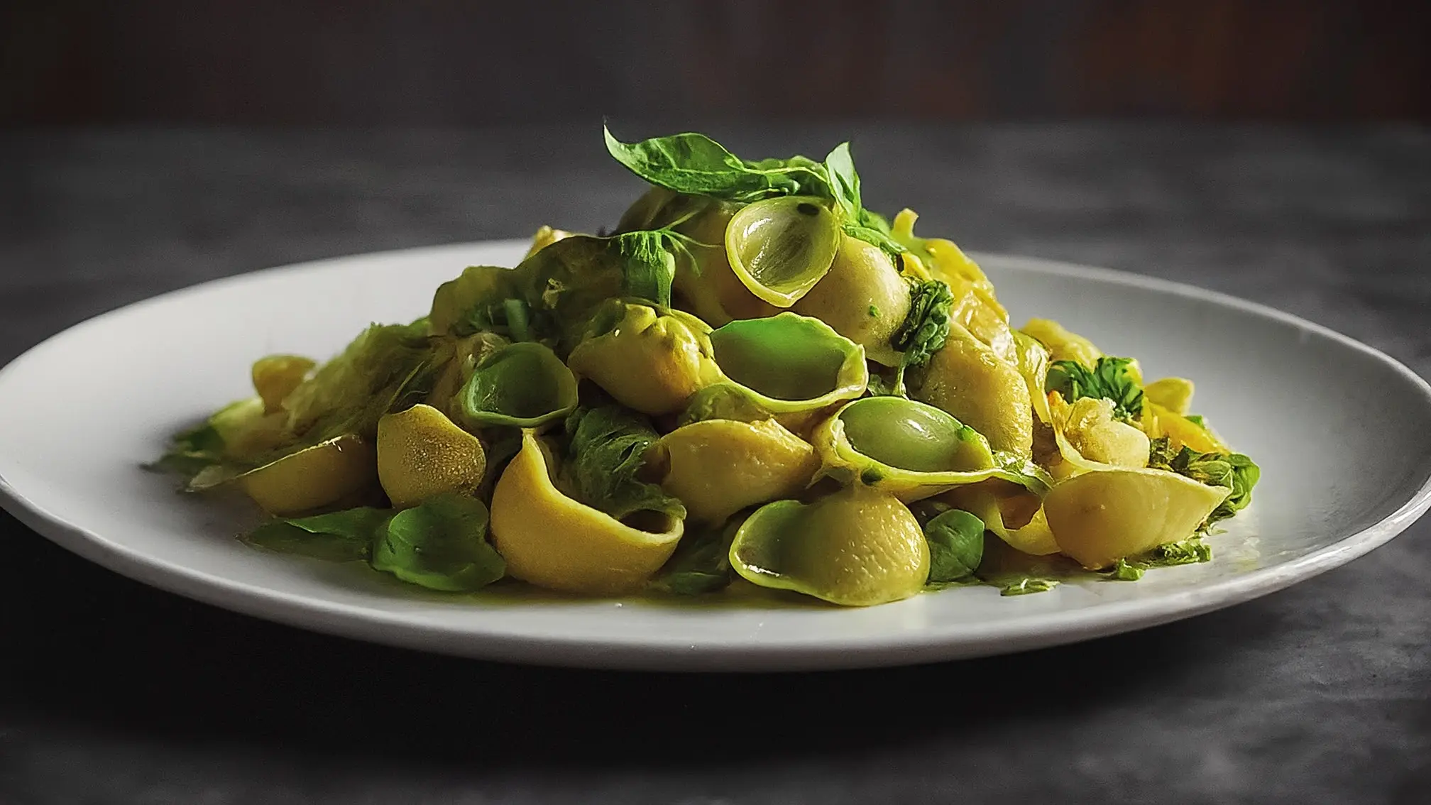 Plato de pasta sin gluten con cubos de calabacín y una generosa capa de pesto verde brillante, decorado con hojas frescas de albahaca.